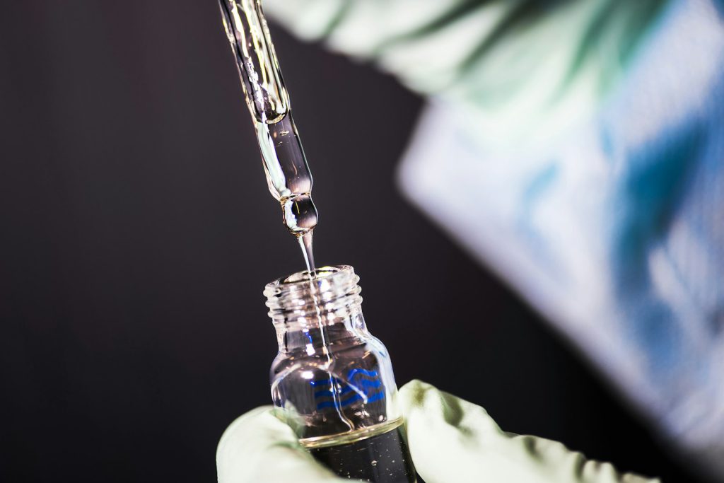 A pipette filling a laboratory sample vial